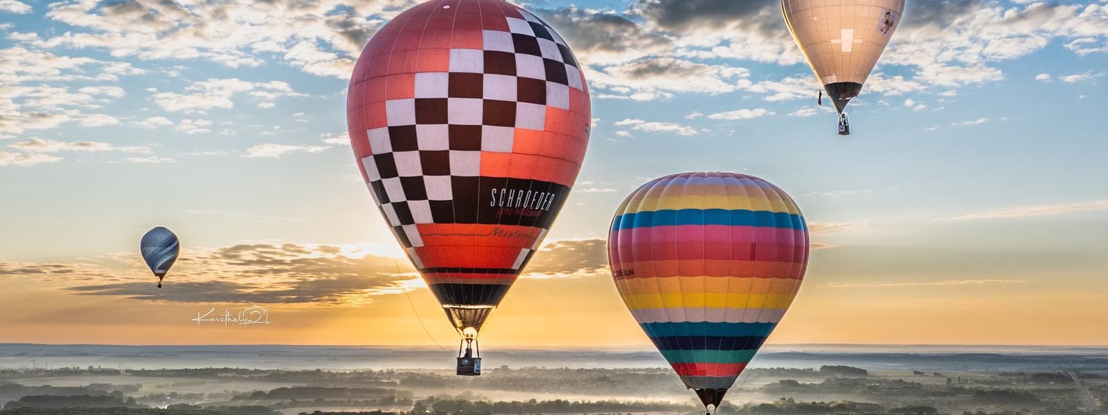 Hőlégballonok emelkednek a hajnali táj felett - új vezetés érkezése